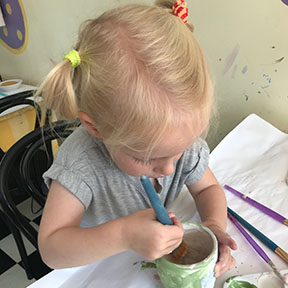 a child painting bisque pottery